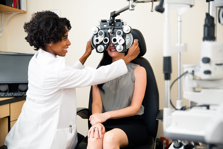 Optometrist using phoropter as she examines a patients eyes