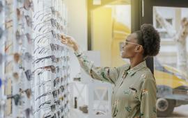 Young black woman at a glasses dispensary looking at different styles of sunglasses