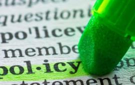 green highlighter pen over word policy in a dictionary