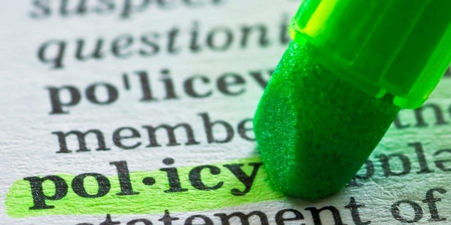 green highlighter pen over word policy in a dictionary
